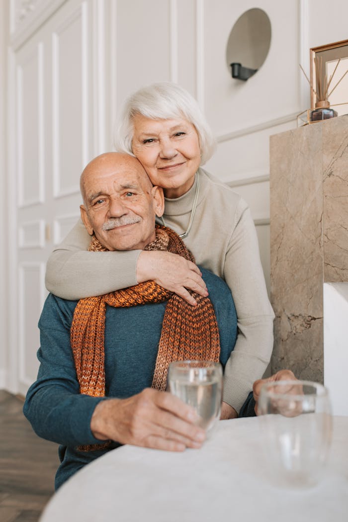 Elderly couple enjoying a warm and loving moment indoors, drinking together.